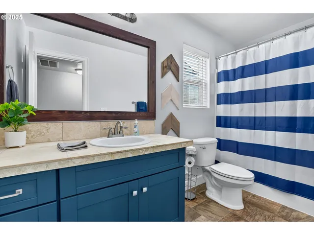 a bathroom with a sink a toilet a large mirror and shower curtain