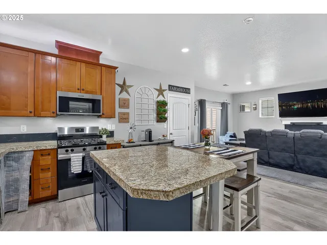 a kitchen with stainless steel appliances granite countertop a stove top oven a sink dishwasher a dining table and chairs with wooden floor