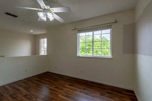 a view of empty room with wooden floor and fan