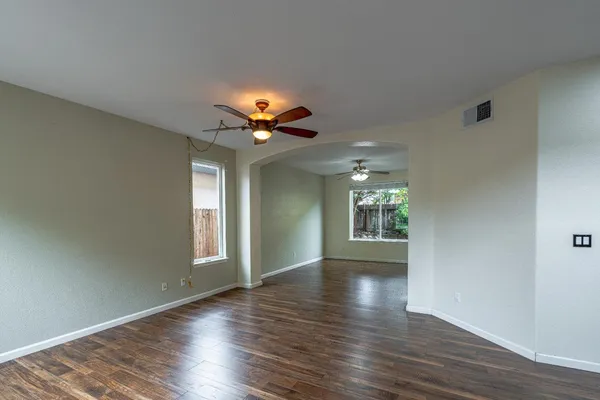 a view of an empty room with window and wooden floor