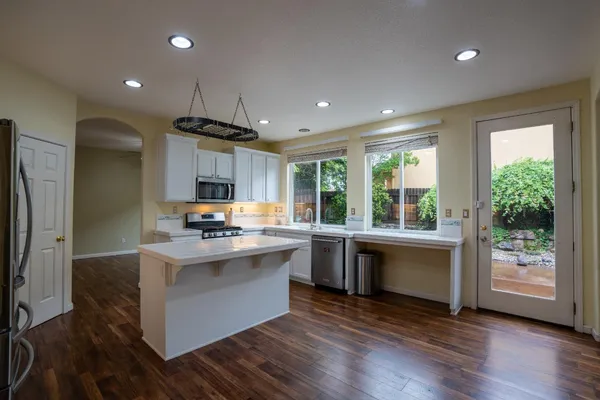a kitchen with kitchen island granite countertop a sink stove and refrigerator