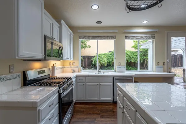 a kitchen with stainless steel appliances granite countertop a sink a stove and a refrigerator