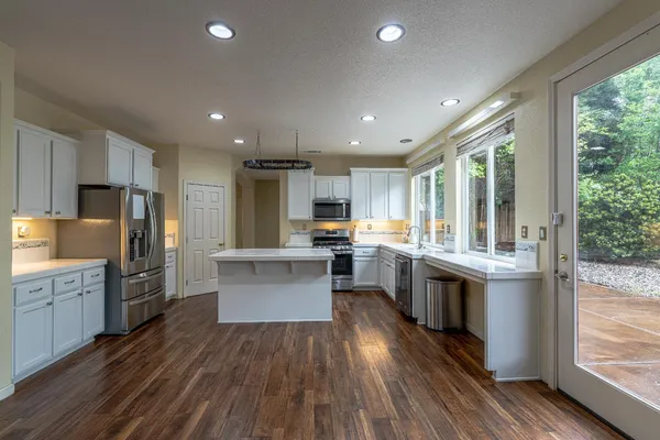 a kitchen with a sink wooden floor and stainless steel appliances