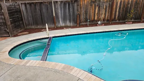 a view of a swimming pool with a yard and wooden fence
