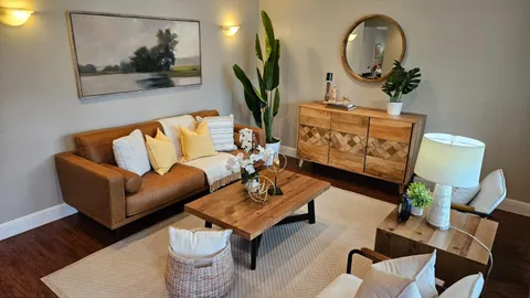 a living room with furniture a mirror and wooden floor