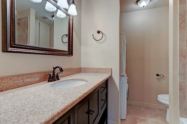 a bathroom with a granite countertop sink a toilet and a mirror