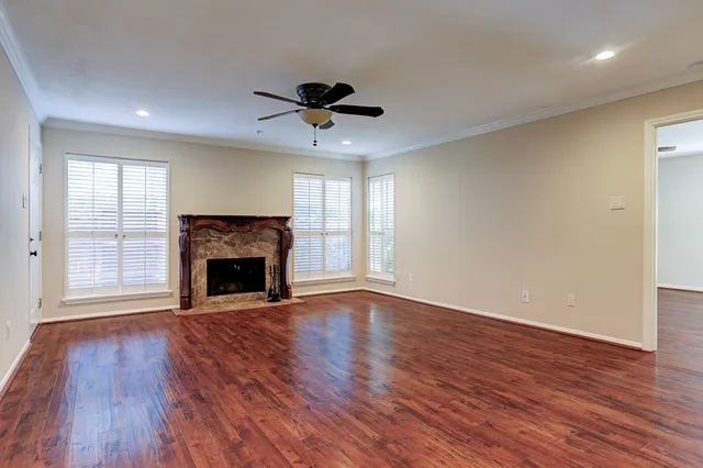 a view of an empty room with wooden floor fireplace and a window