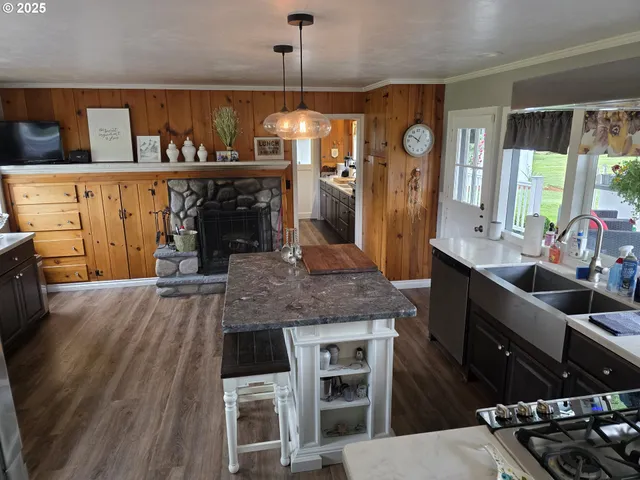 a kitchen with stainless steel appliances granite countertop a stove a refrigerator a sink a dining table and chairs with wooden floor