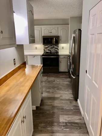 a kitchen with stainless steel appliances granite countertop a refrigerator a stove and a sink with wooden floor