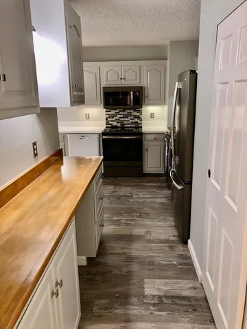 a kitchen with stainless steel appliances granite countertop a refrigerator a stove and a sink with wooden floor