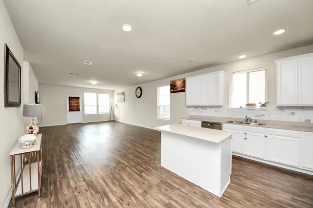 a kitchen with a sink cabinets wooden floor and a window
