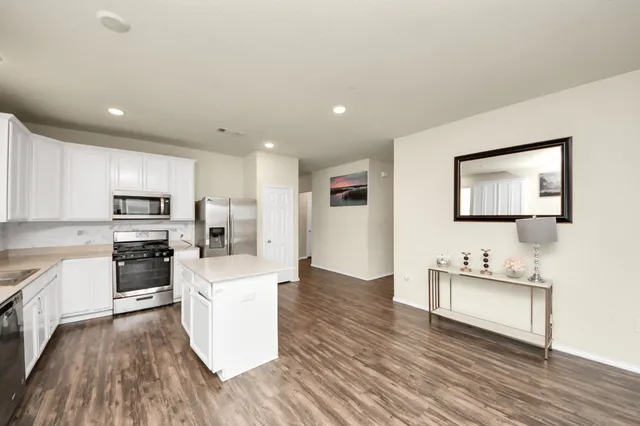 a large kitchen with cabinets wooden floor and stainless steel appliances