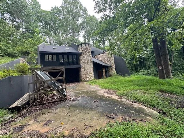 a view of a wooden house with a yard and large trees