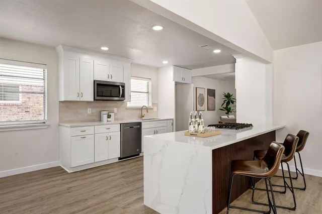 a kitchen with a stove a sink a microwave a dining table and chairs