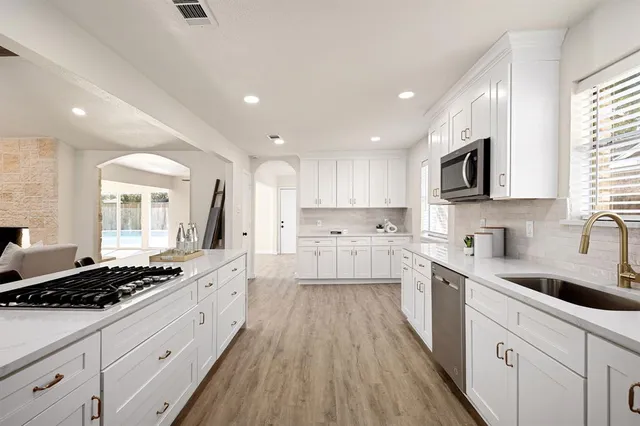 a large kitchen with stainless steel appliances granite countertop a lot of counter space and wooden floors