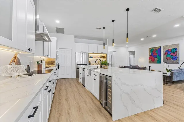 a large white kitchen with kitchen island a large counter space a sink a window and stainless steel appliances