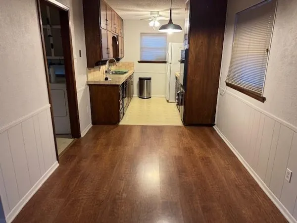 an empty room with wooden floor windows and chandelier fan