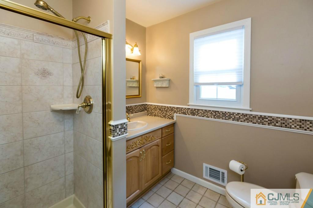 104 South Cliff Road Colonia, NJ 07067 - Photo 16 of 25 a bathroom with a granite countertop sink a mirror and a shower
