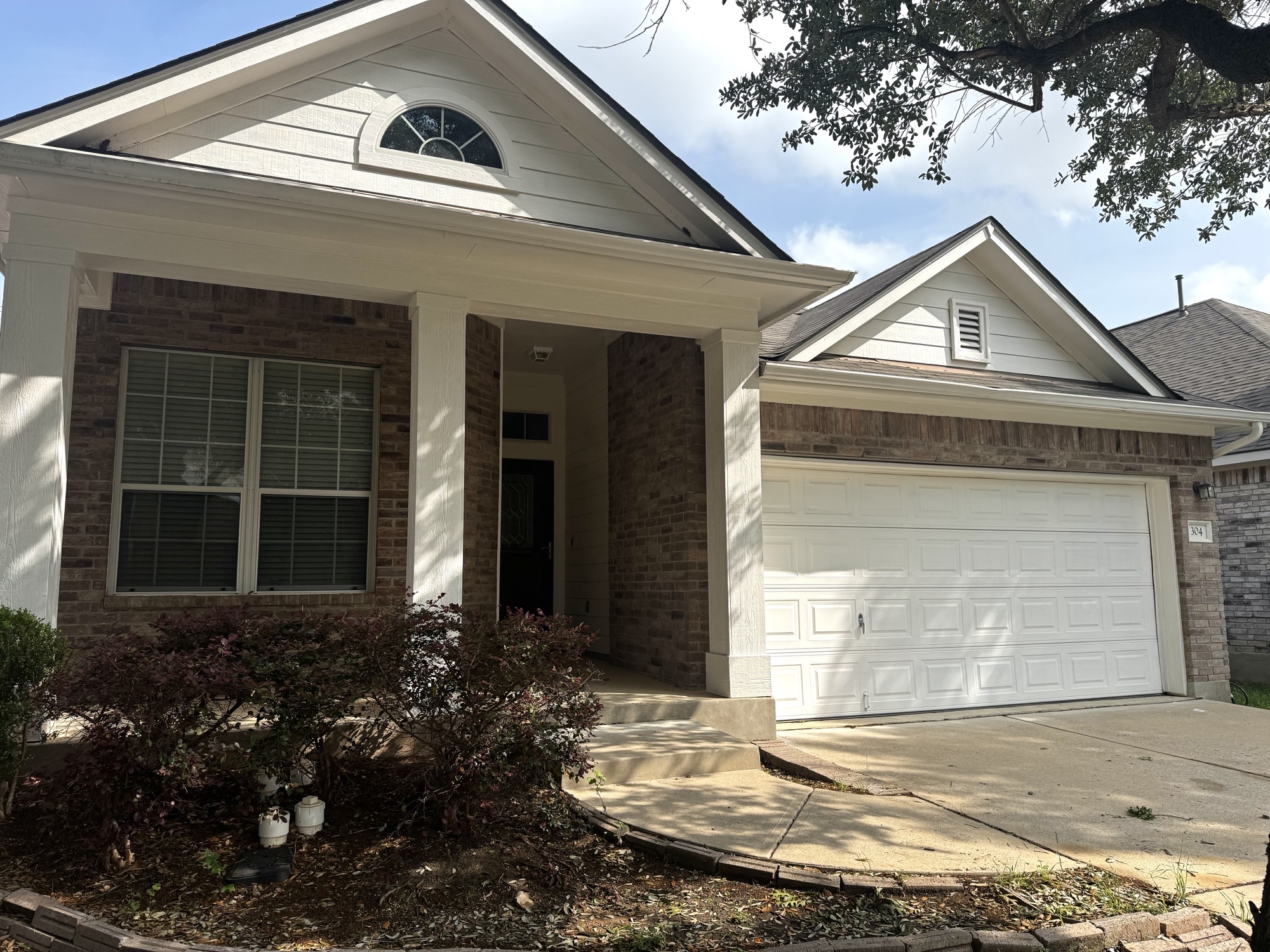 Brick and siding exterior featuring a covered entry porch supported by white columns