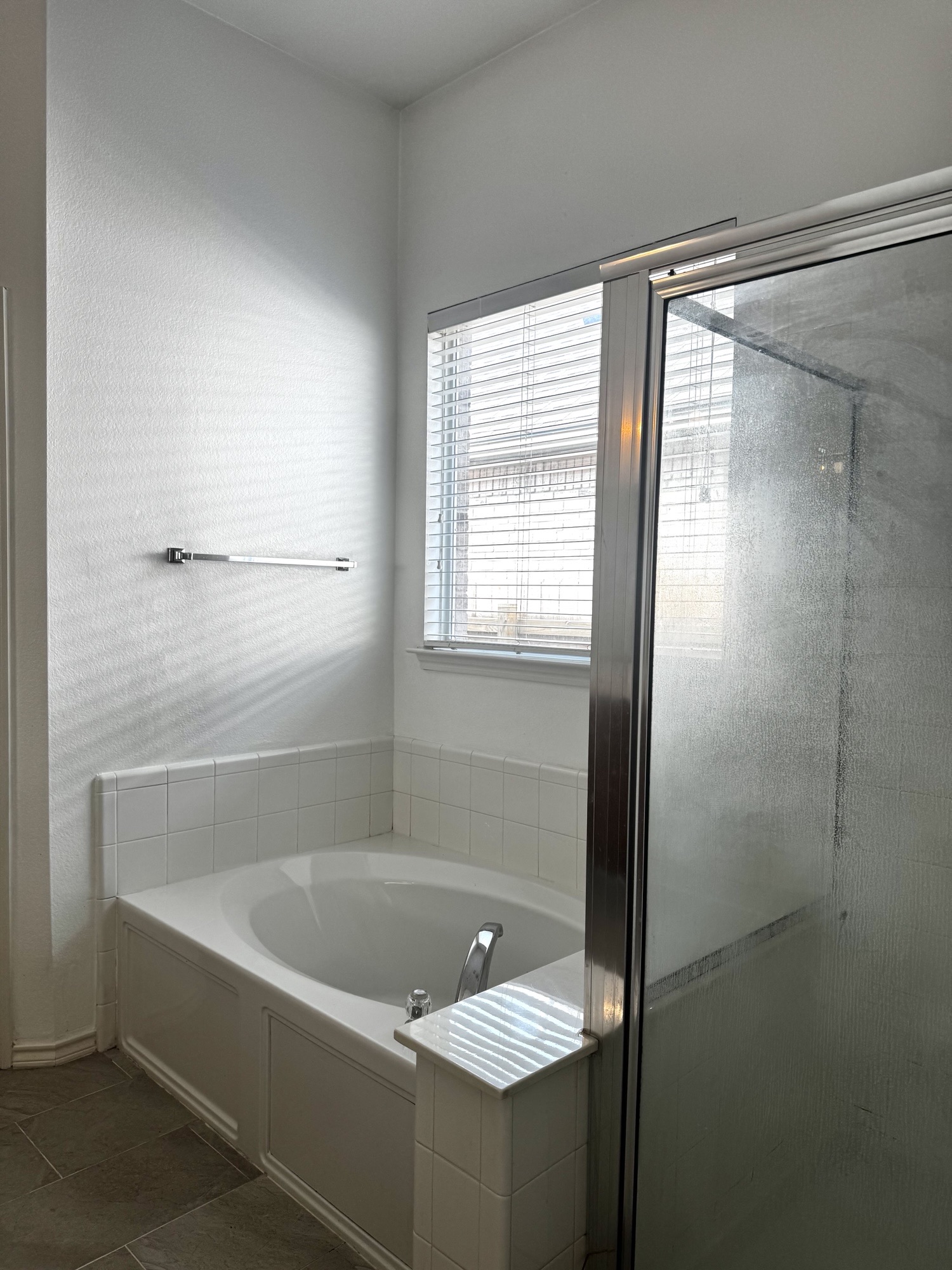304 Valona Loop Round Rock, TX 78681 - Photo 11 of 15 Recessed soaking tub with white tile surround, privacy window with blinds, and brushed chrome fixtures