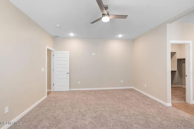 an empty room with closet and a ceiling fan