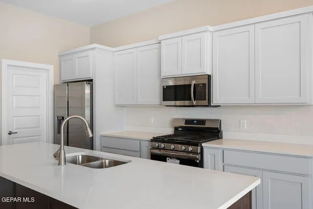 a kitchen with a sink and a stove top oven with white stainless steel appliances