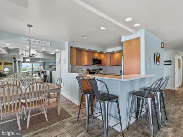 a kitchen with stainless steel appliances kitchen island granite countertop a dining table chairs and a sink