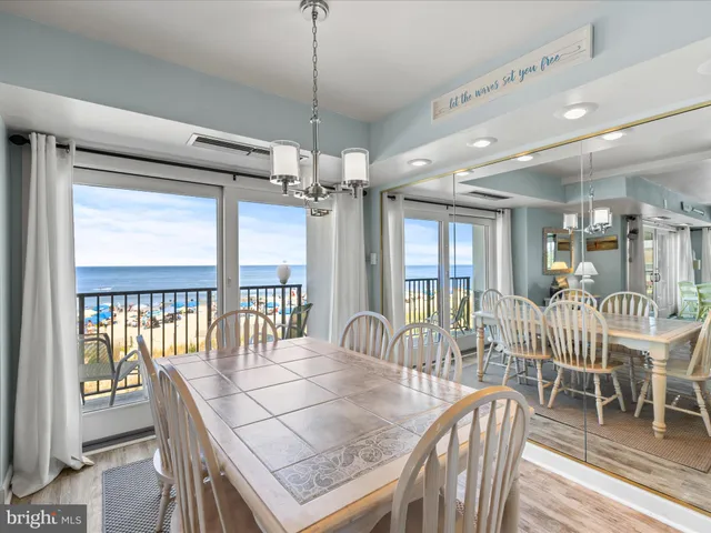 a view of a dining room and livingroom with furniture wooden floor a chandelier