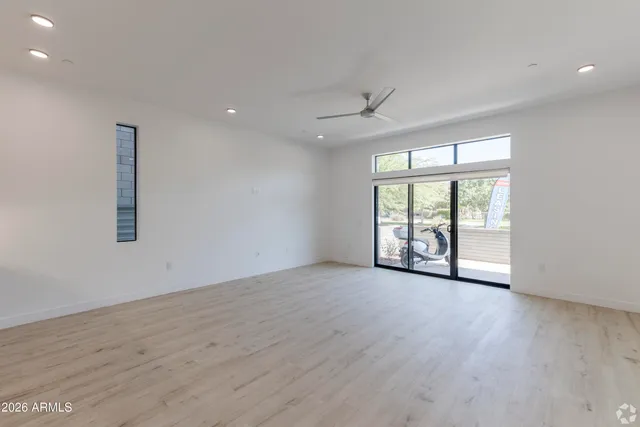 a view of an empty room with a window and wooden floor