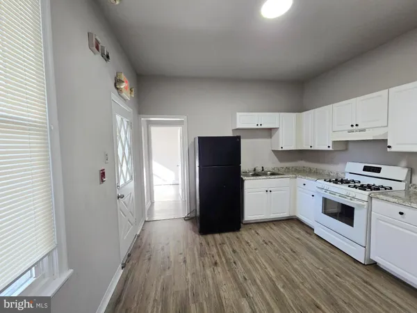 a kitchen with a refrigerator stove and white cabinets with wooden floor
