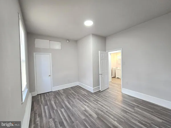 a view of an empty room with wooden floor and closet