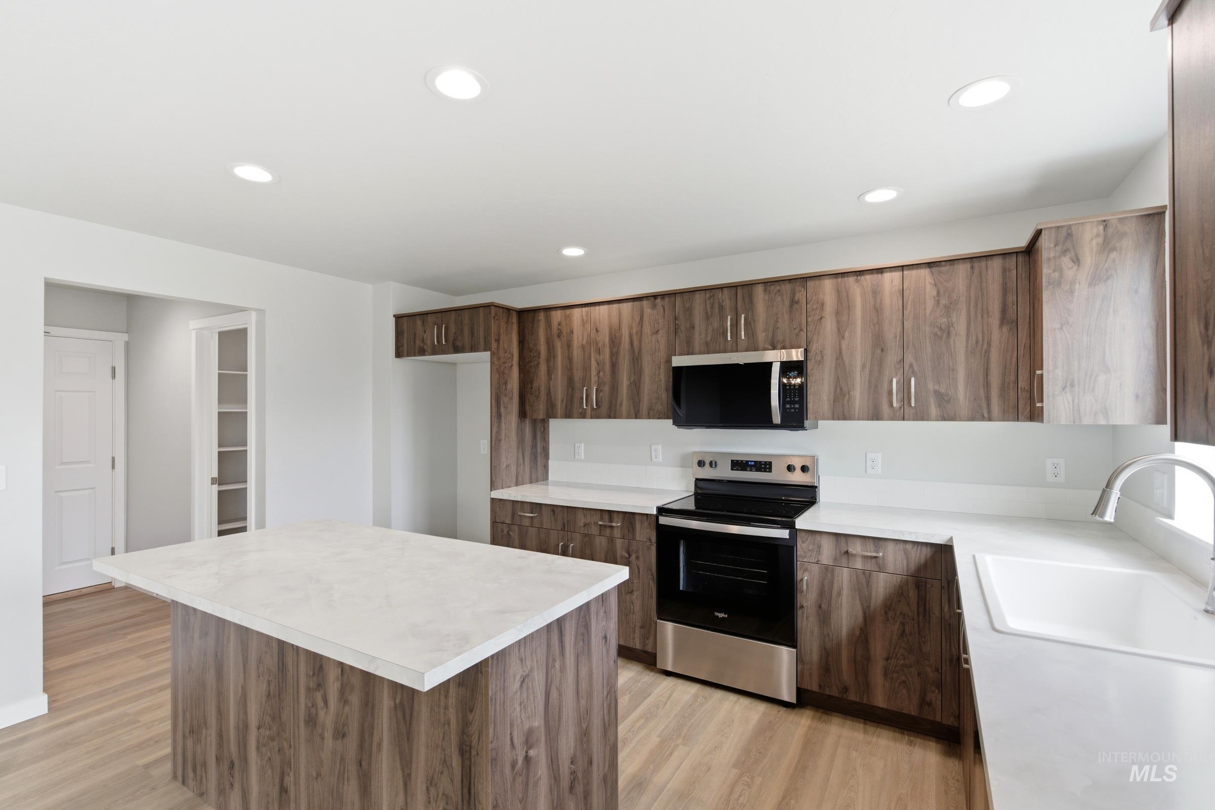 16558 Dunning Way Caldwell, ID 83607 - Photo 5 of 35 Kitchen featuring wood-finish cabinetry, light countertops, stainless steel appliances, a center island, and recessed lighting