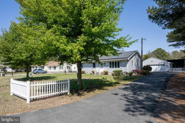 a view of a house with a small yard and a large tree