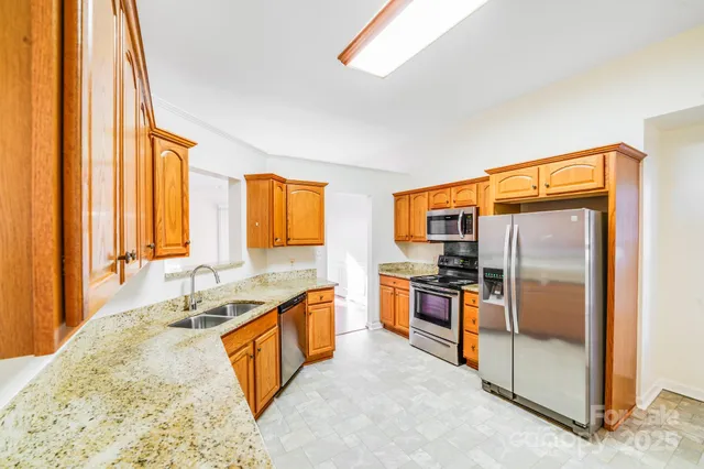 a kitchen with stainless steel appliances granite countertop a sink and a refrigerator