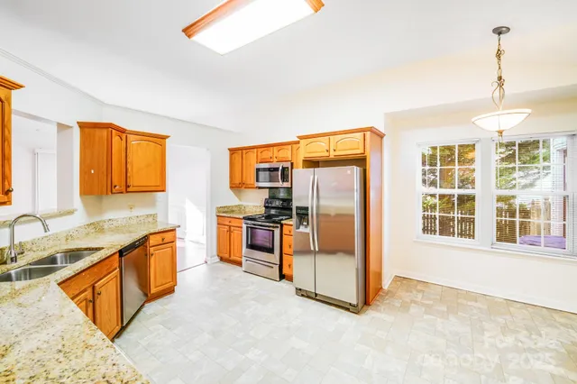 a view of a kitchen with stainless steel appliances granite countertop a refrigerator and a sink