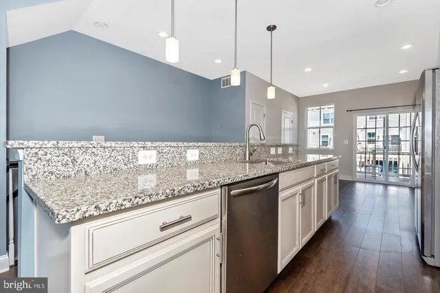 a large kitchen with granite countertop a large counter top a sink stainless steel appliances and cabinets