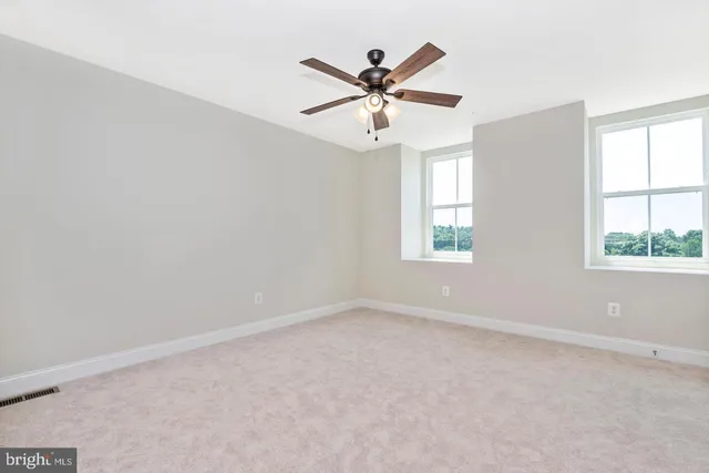 an empty room with window and ceiling fan