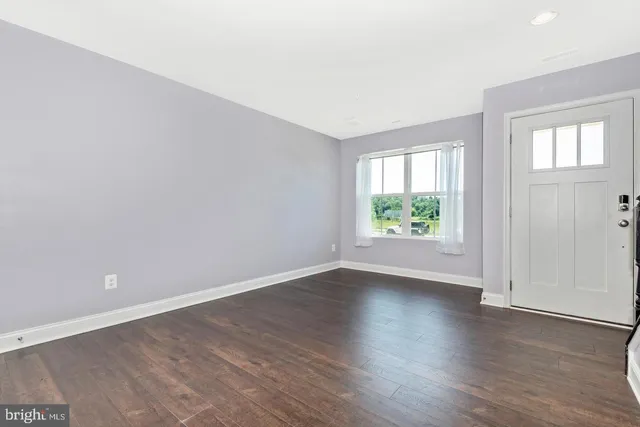 an empty room with wooden floor and window