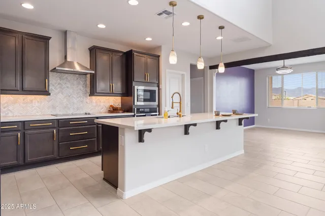 a large kitchen with stainless steel appliances kitchen island granite countertop a stove a sink a refrigerator and a microwave