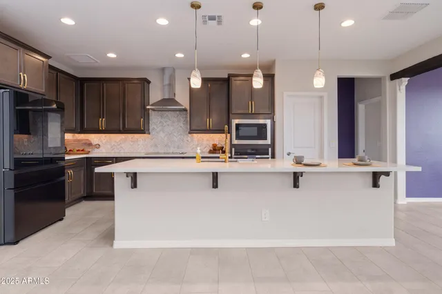 a kitchen with stainless steel appliances kitchen island granite countertop a refrigerator a stove and a sink with wooden cabinets