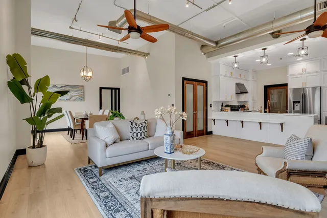 a living room with furniture kitchen view and a wooden floor