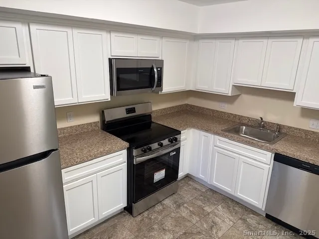 a kitchen with white cabinets and black appliances
