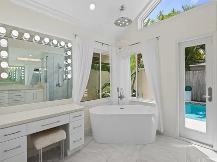 a bathroom with a tub a sink and a large mirror