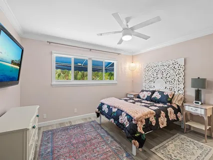 a bedroom with a bed a window and a flat screen tv