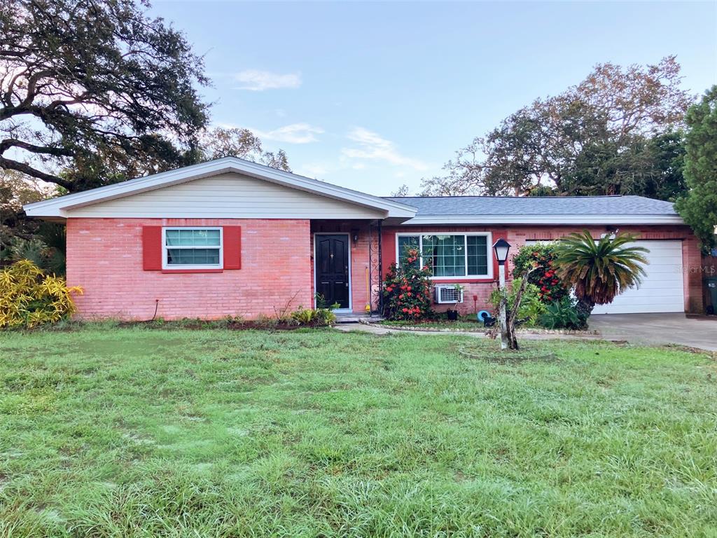 1221 12th Court Southwest Largo, FL 33770 - Photo 1 of 13 a front view of a house with a yard and garage
