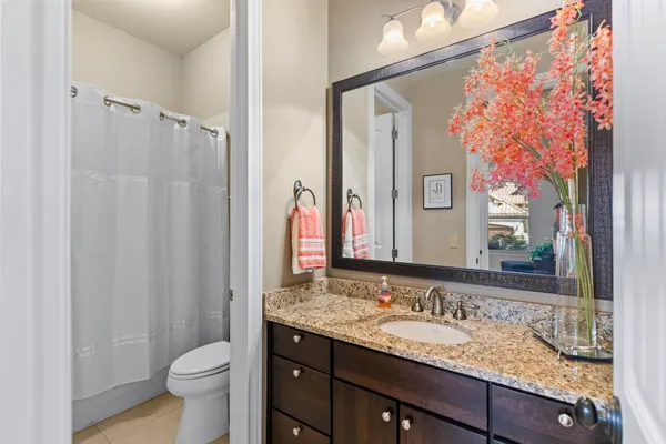 a bathroom with a granite countertop sink toilet and mirror