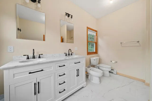 a bathroom with a granite countertop toilet sink and mirror