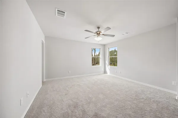 an empty room with windows and fan