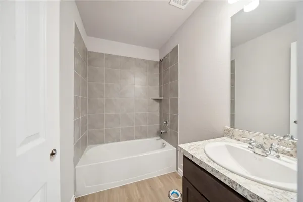 a bathroom with a granite countertop bathtub shower sink vanity and toilet
