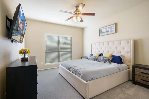 a bedroom with a bed and a flat tv screen on dresser